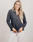 Woman wearing a dark gray sweater with a patterned collar against a plain background