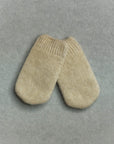 Pair of beige knitted baby mittens on a gray background