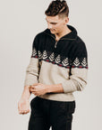 Man wearing a black and beige patterned sweater against a plain background