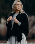 Woman wearing a black wrap over a gray sweater with a blurred natural background