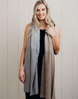 Woman wearing a long, gradient scarf against a neutral background