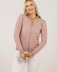 Woman wearing a pink zip-up cardigan against a white background