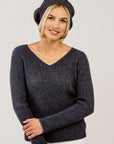 Woman wearing a dark gray ribbed sweater and matching beret hat against a plain background