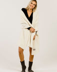 Woman wearing a cream-colored stole over her shoulders  and grey socks on a white background
