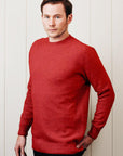 Man wearing a red sweater against a white wall