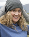 Woman wearing aa silver beanie and wrist warmer outside.