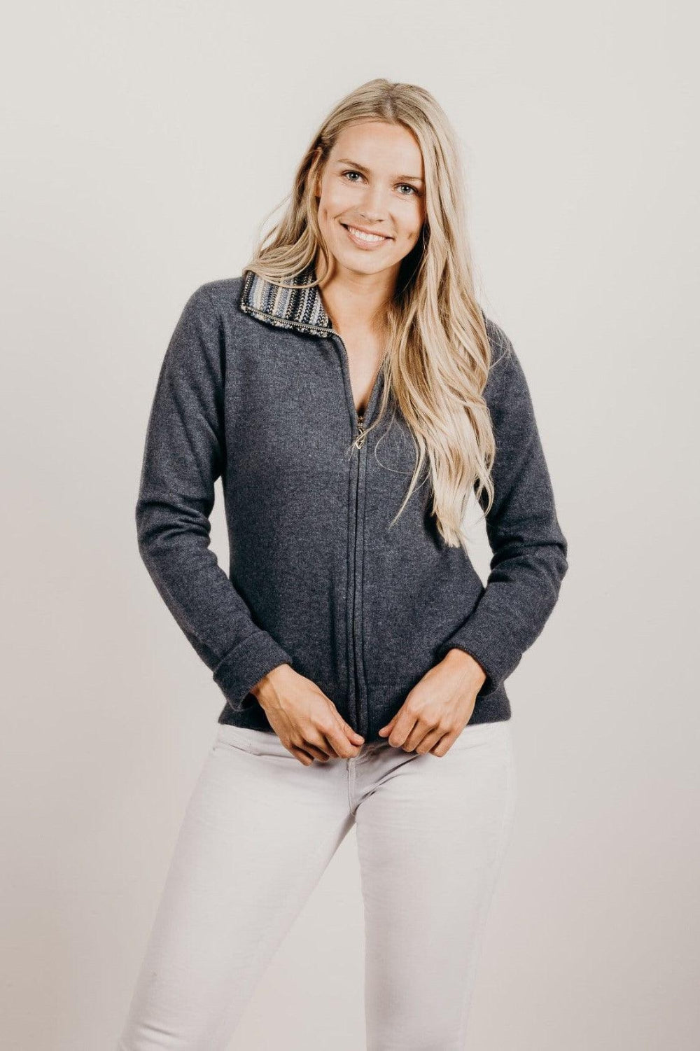 Woman wearing a dark gray sweater with a patterned collar against a plain background