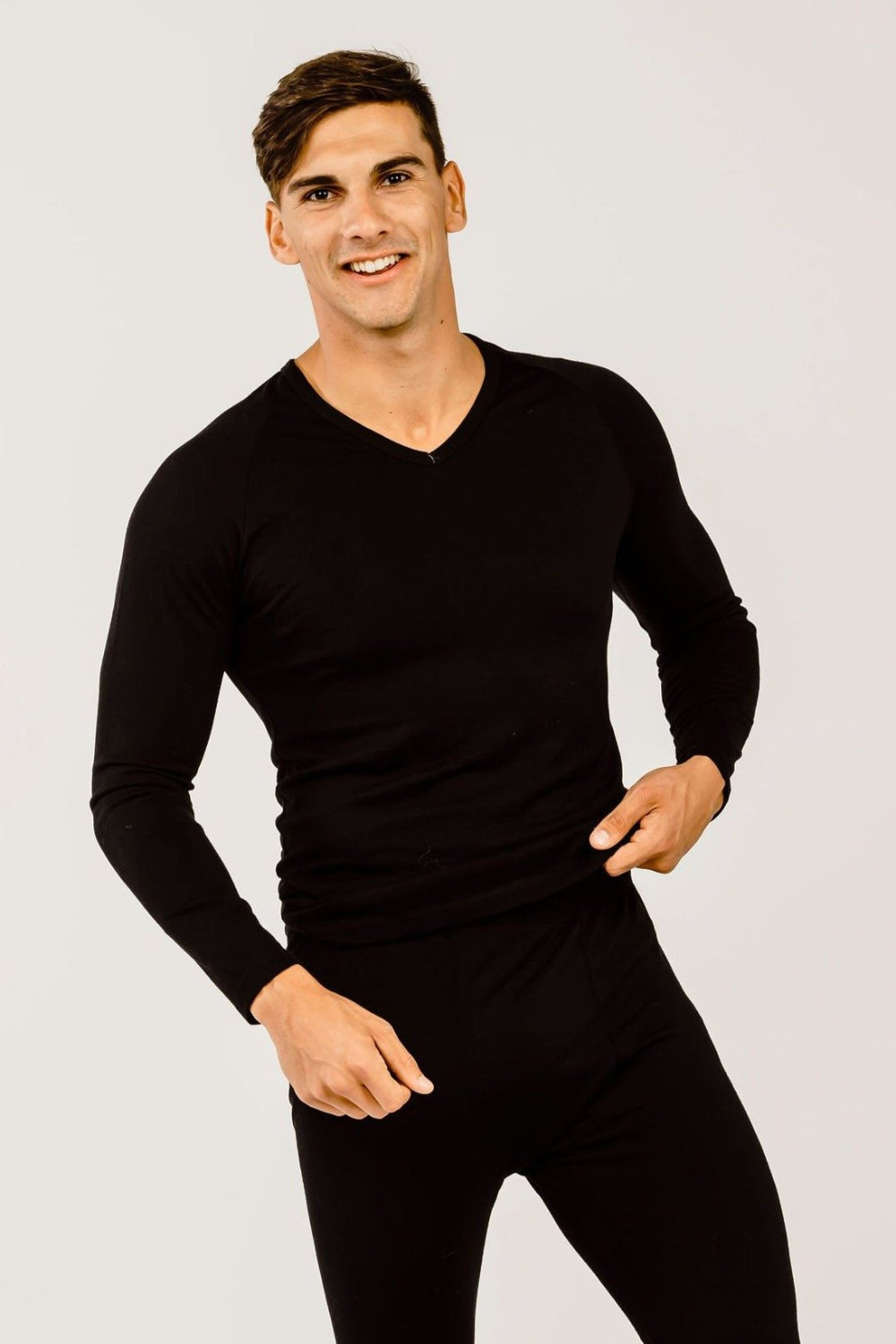 A man wearing a black long-sleeved merino wool V-neck sweater.