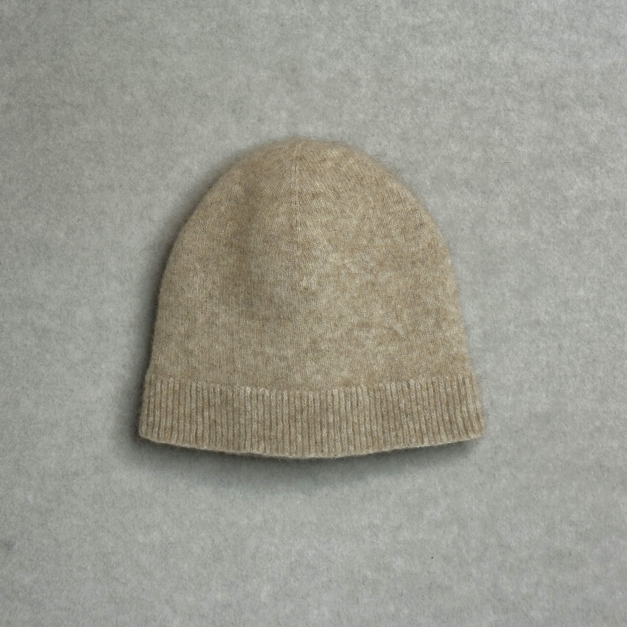 Beige knit baby beanie on a gray background