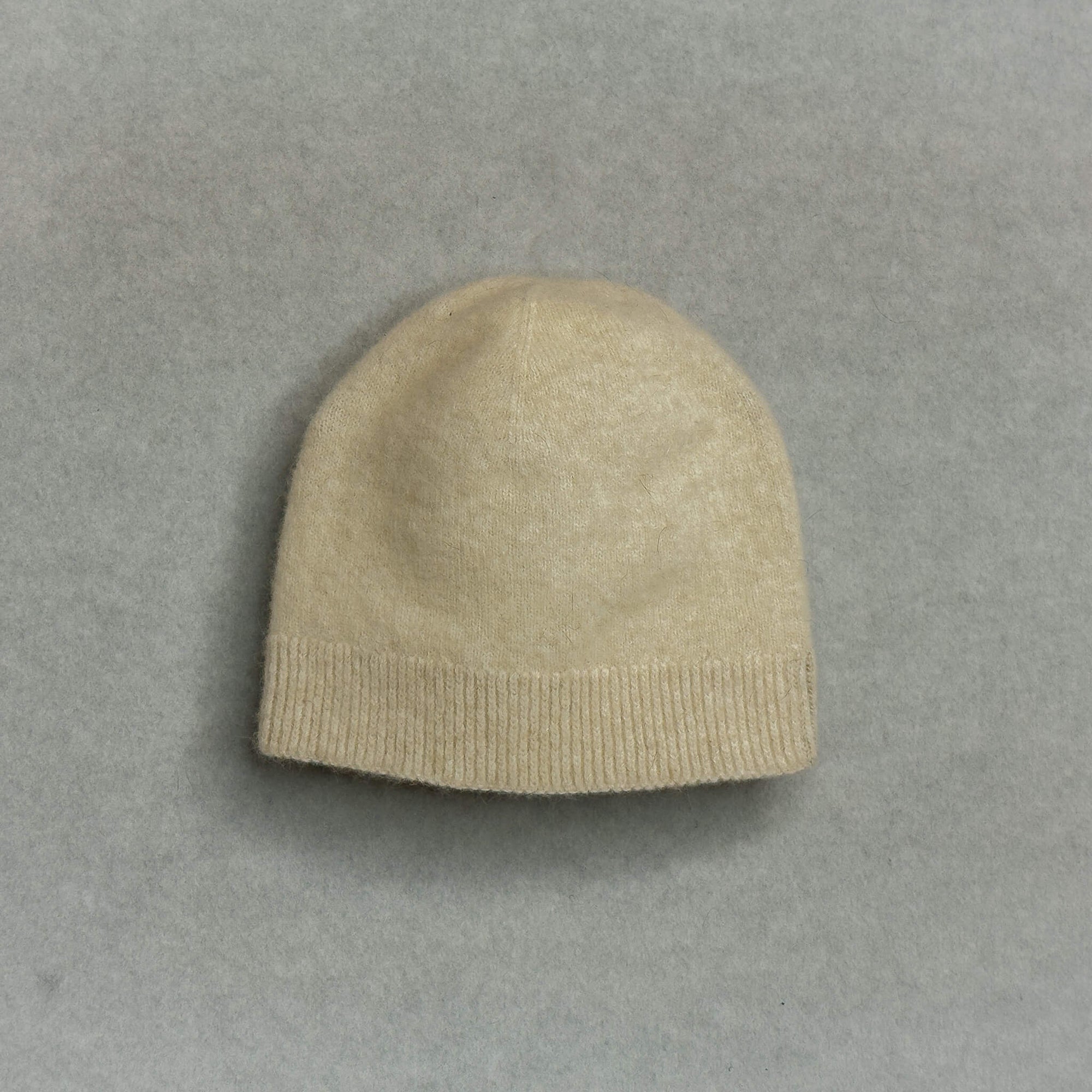 Beige knit baby beanie on a gray background