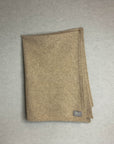 Beige baby blanket with a brand label on a gray background