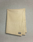 Beige baby blanket with a brand label on a gray background