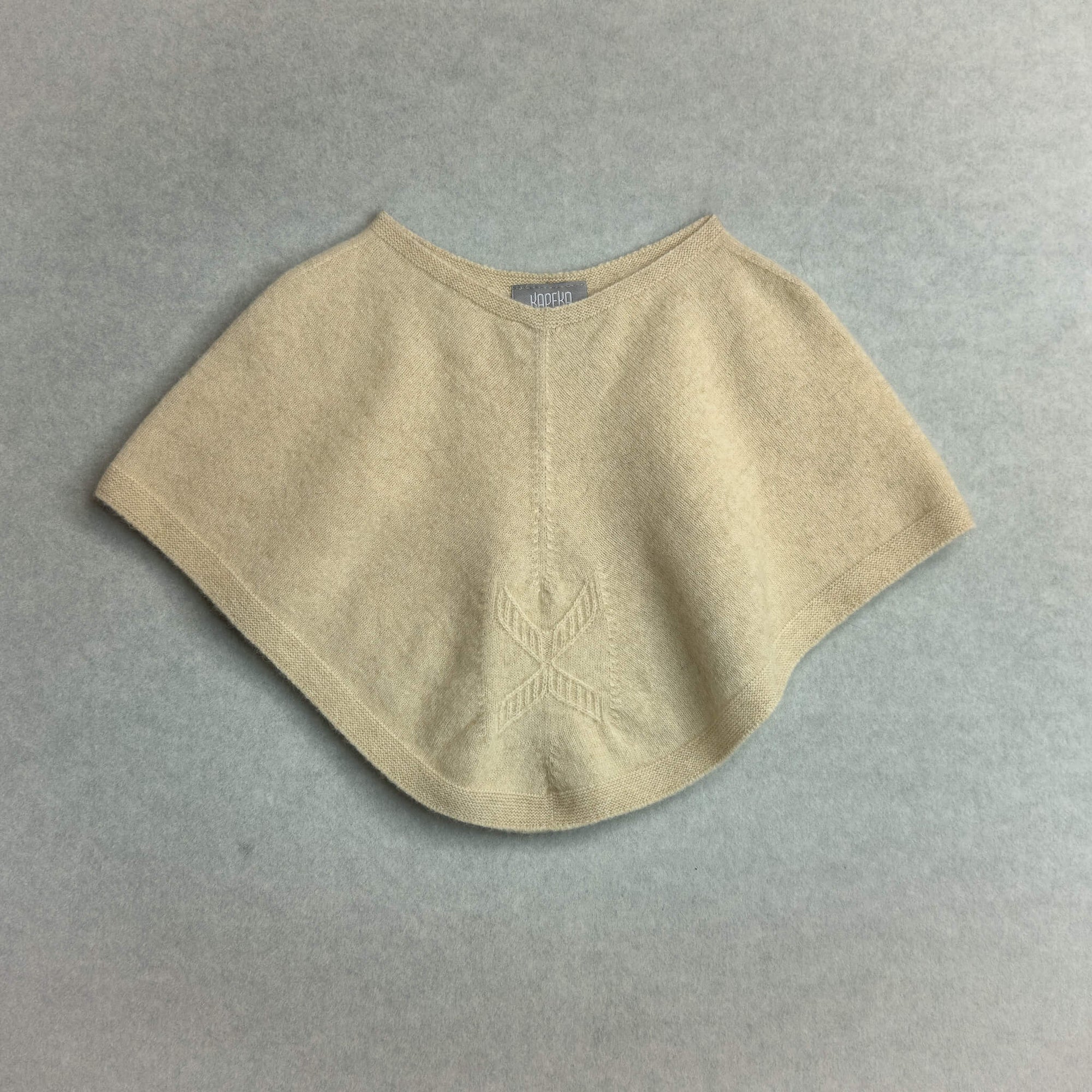 Beige knitted poncho on a gray background