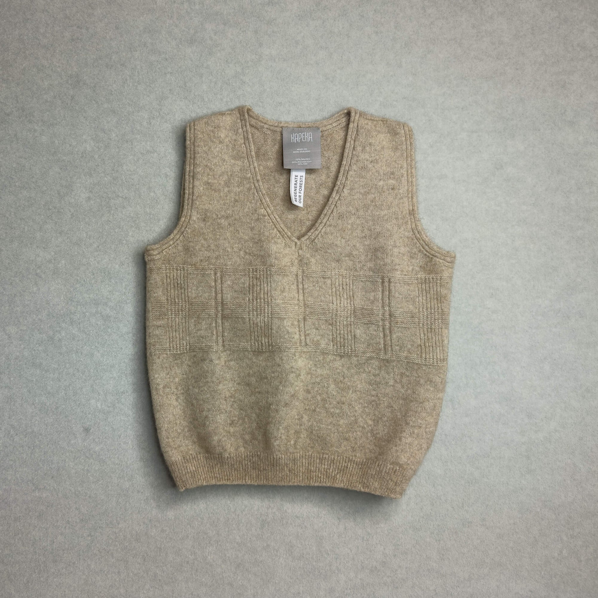 Brown knitted baby vest with a label on a gray background