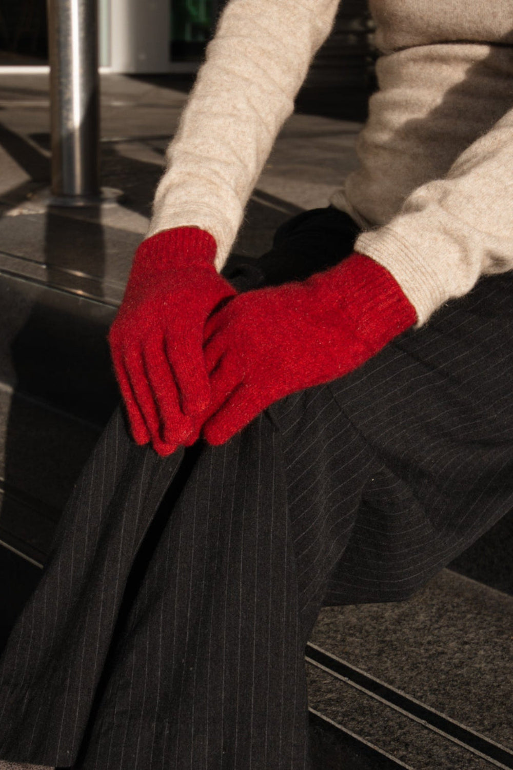 Person wearing red gloves sitting on steps outdoors
