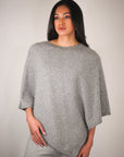 Woman wearing a gray poncho against a plain background
