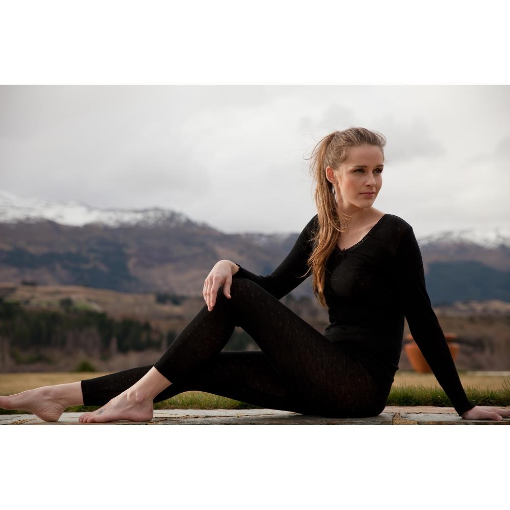 Woman in black outfit sitting outdoors with mountains in the background