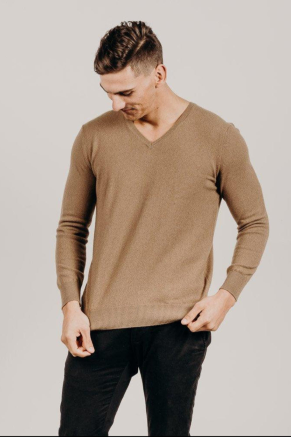 Man wearing a light brown v Classic Cervelt sweater and black pants - Kapeka NZ, Made from New Zealand Red Deer Fibre. Very Soft and rare Fibre. Only made in New ZealandCervelt Luxury V Neck -