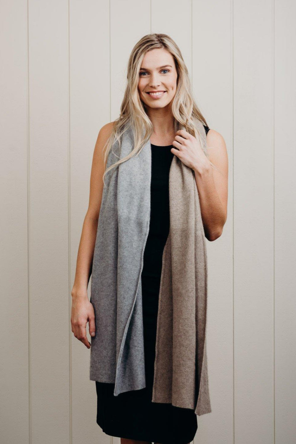 Woman wearing a long, gradient scarf against a neutral background
