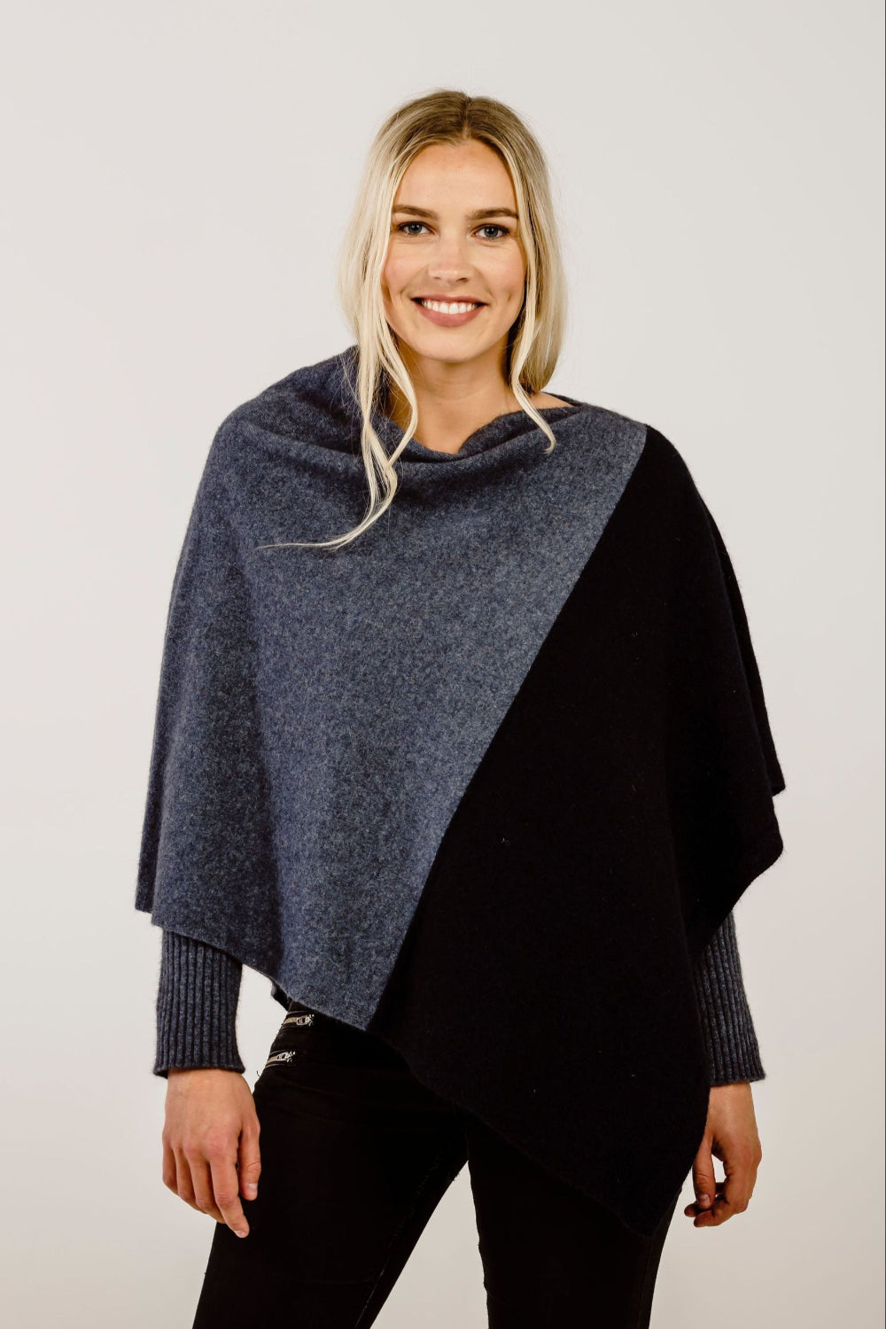 Woman wearing a two-tone poncho with gray and navy colors on a plain background