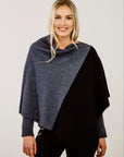 Woman wearing a two-tone poncho with gray and navy colors on a plain background