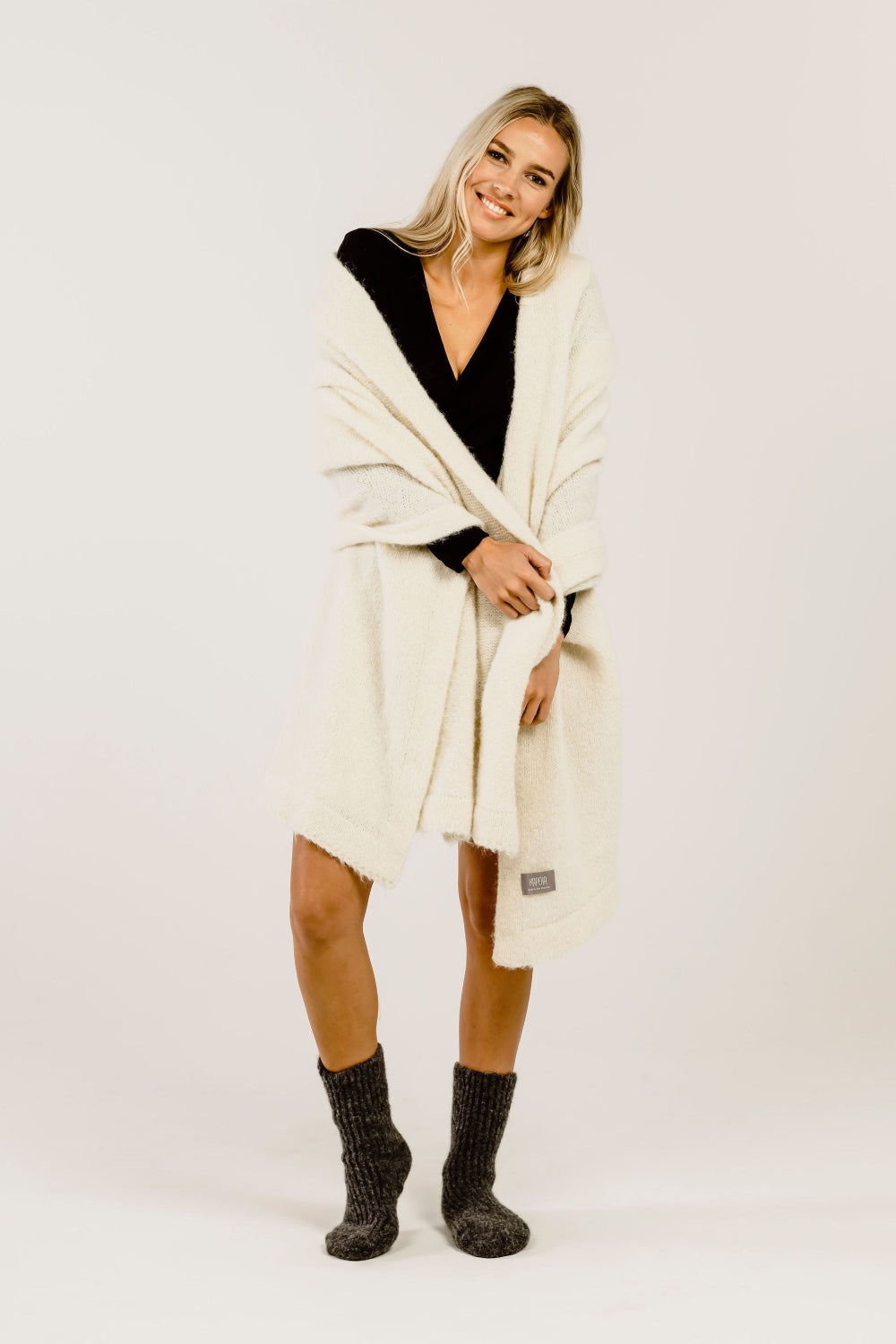 Woman wearing a cream-colored stole over her shoulders  and grey socks on a white background