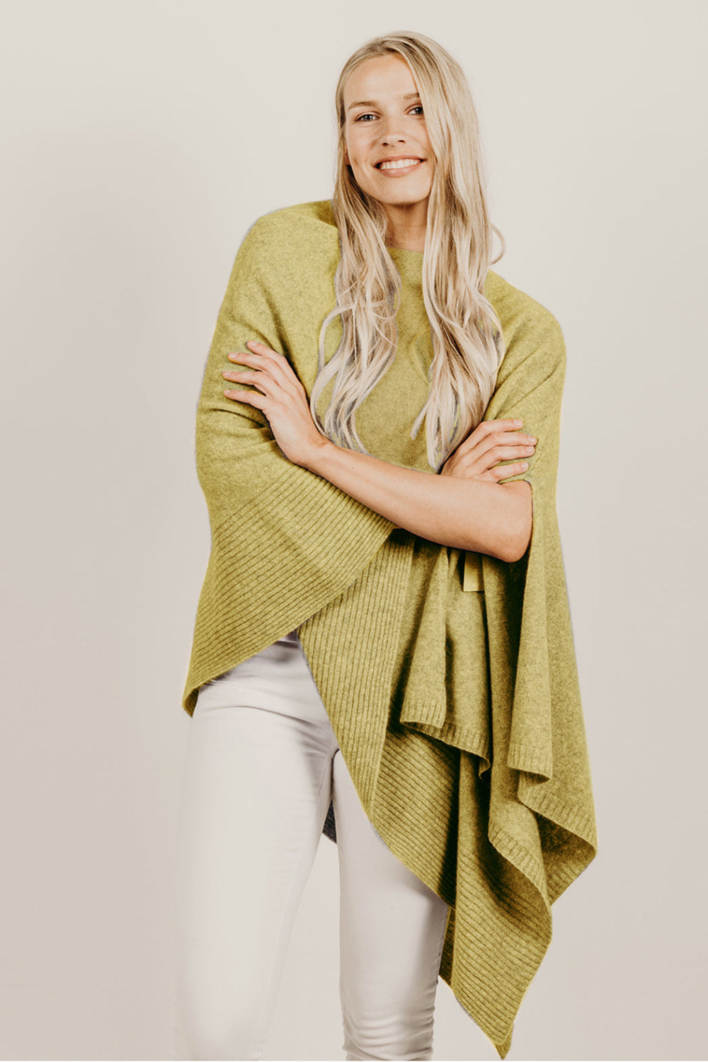 Woman wearing a green poncho against a plain background