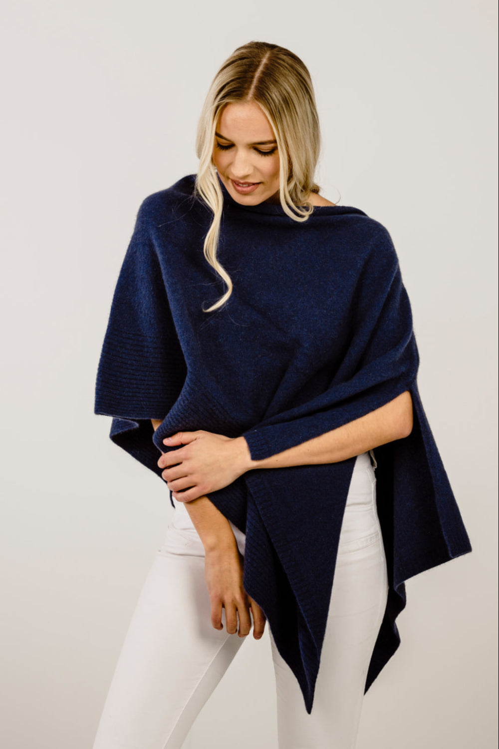 Woman wearing a navy blue poncho against a plain background