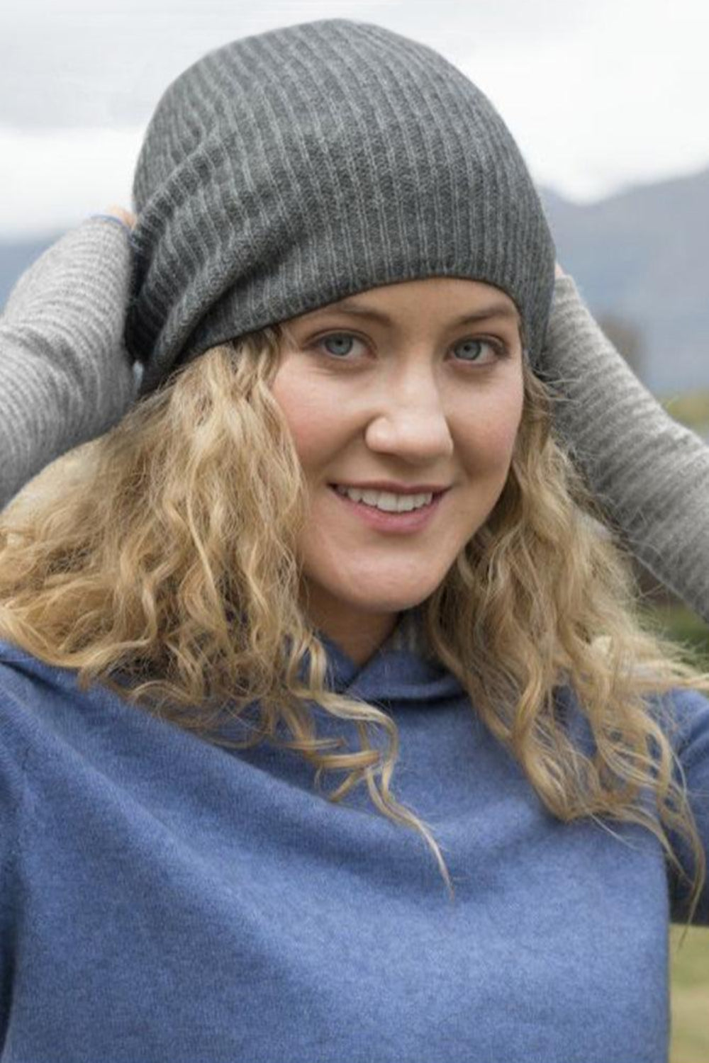 Woman wearing aa silver beanie and wrist warmer outside.